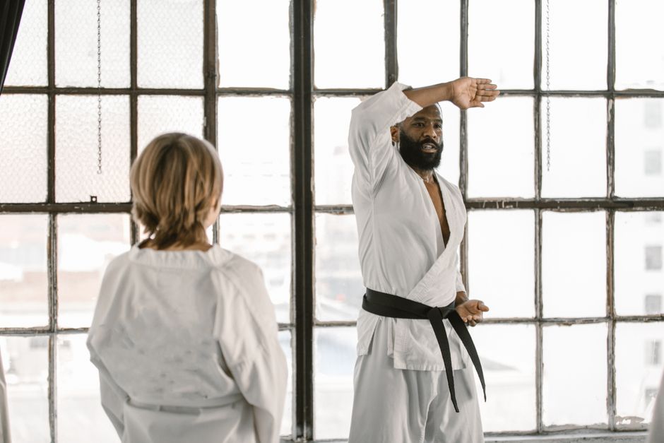 Karate instructor teaching martial arts class in a studio with large windows.